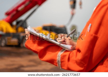 An engineer or foreman is checking on safety checklist form of lifting crane at the drilling rig work site. Industrial safe working concent, close-up and selective focus.