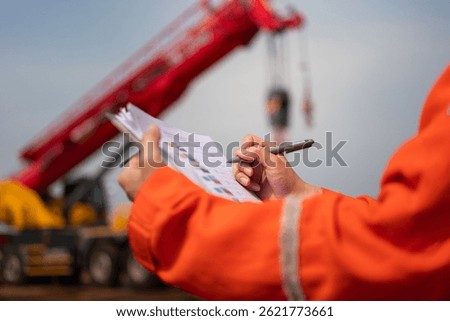 An engineer or foreman is checking on safety checklist form of lifting crane at the drilling rig work site. Industrial safe working concent, close-up and selective focus.