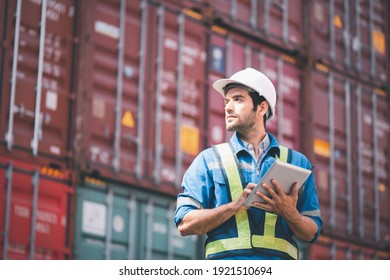 Engineer or foreman holding tablet and wears PPE looking at left side to checking inventory or job details with cargo container background. Engineering site and working with technology concept. - Shutterstock ID 1921510694