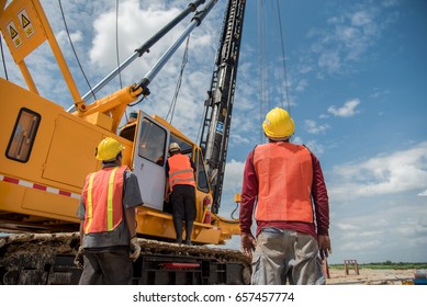 Engineer and foreman looking at heavy machine Assembly concrete pile driving truck  for  working against building construction crane
