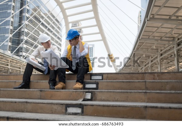 Engineer group and worker\
meeting,Happy team discussion with construction on site work sit on\
the stairs.