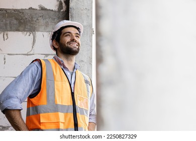 engineer handsome man or architect looking forward with white safety helmet in construction site. Standing at modern building construction. Worker asian man working project building