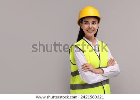 Engineer in hard hat on grey background, space for text