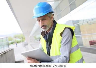 Engineer With Hard Hat Using Tablet Outside Building