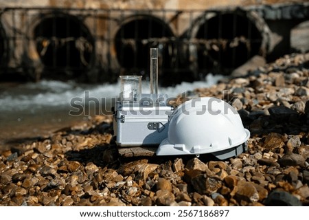 Engineer Hardhat and connected water sampling device equipment appears to collecting or analyzing data the water quality industrial wastewater discharged into natural water concept.