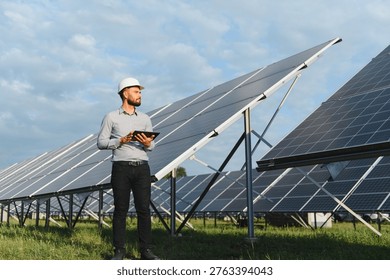 Engineer in hardhat holding tablet, checking solar power plant installation. Concept of green technology and sustainable energy