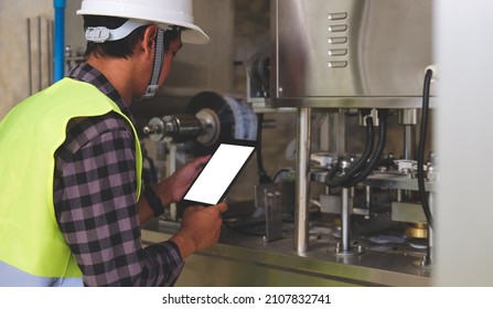 Engineer in hardhat is using digital tablet in a factory.