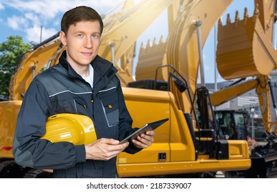 Engineer With A Helmet And Digital Tablet On The Background Of Construction Vehicles