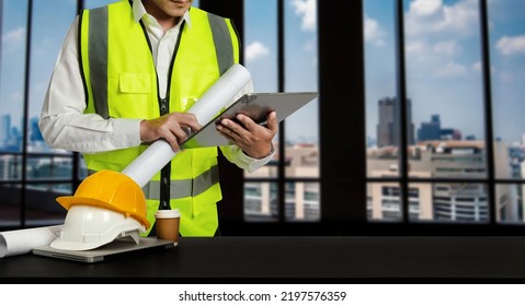 Engineer In Helmet For Workers Security On Office Buildings And Management On The Construction Drawing Plan Near Laptop Working In Engineering Tools On Desk 
