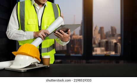 Engineer In Helmet For Workers Security On Office Buildings And Management On The Construction Drawing Plan Near Laptop Working In Engineering Tools On Desk
