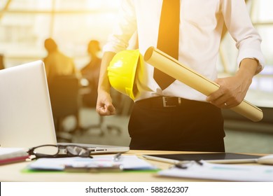 Engineer Hold Security Helmet And Blueprint Paper Construction Drawing Plan Near Laptop Computer,Architect Working In Office,Engineering Tools On Desk At Site Project