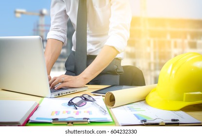 Engineer Hold Security Helmet And Blueprint Paper Construction Drawing Plan Near Laptop Computer,Architect Working In Office,Engineering Tools On Desk At Site Project