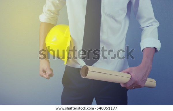 engineer hold security\
helmet and blueprint paper construction drawing plan.selective\
focus.vintage color