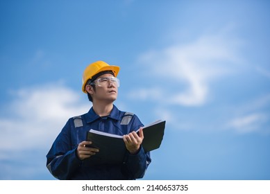 An Engineer is holding a document and looking away.