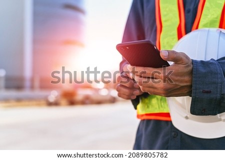 Engineer holding helmet and use phone send work data report 