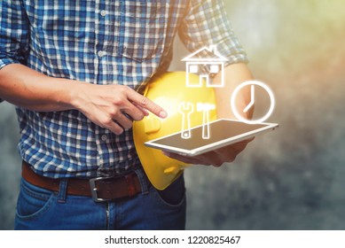 Engineer holding helmet and using tablet checking for project Construction.