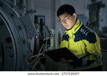 Engineer inspecting operational status of large industrial equipment in a factory workshop