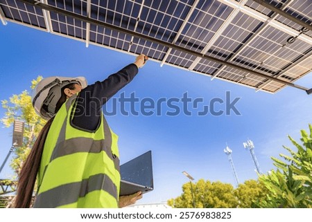 Engineer inspecting solar panels under a solar-powered carport on a sunny day, ensuring optimal performance. Focus on renewable energy, sustainability, green power, and eco-friendly solar solutions.