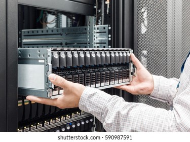 IT Engineer installs enclosure with hard disk drive in the storage system in the rack in datacenter - Powered by Shutterstock