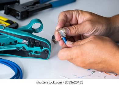 The engineer installs the new connector on the cable using a tool. Crimping tool for internet cable, cable and connectors on the engineer's desktop.