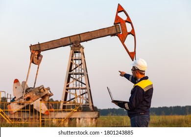 engineer with a laptop on the background of an oil pump