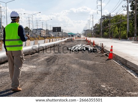 An engineer at a large road construction site. Traffic cones and traffic barriers mark the area in a large infrastructure project. Construction supervisor, work, road structure.