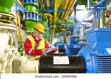 Engineer Looking At A Checklist During Maintenance Work In A Large Industrial Engine Room