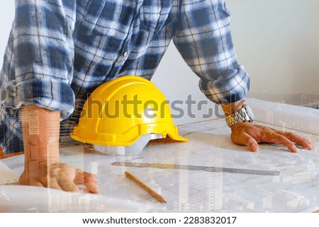 The engineer looks at the construction plan of the building and he works and supervises the construction. He planned the production concept of modern business life modern building overlay