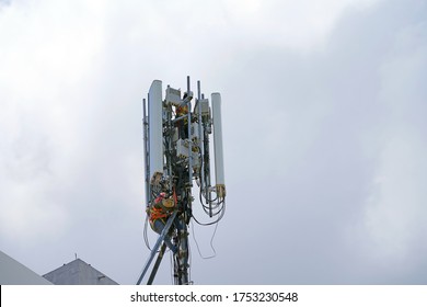 Engineer Maintenance On Telecommunication Tower Doing Ordinary Maintenance & Control To An Antenna For Communication, 3G, 4G And 5G Cellular. Cell Site Base Station On White Clouds Background.