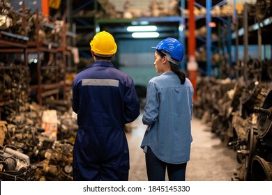 Engineer man and administrator standing in the automotive parts warehouse. Keep the old machine parts. Wearing a safety helmet. Used of vehicle part for recycling in the scrap yard garage. 
 - Powered by Shutterstock