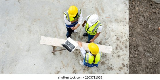 Engineer Man And Architect Teamwork Wear Safety Helmet Meeting At Construction Site With Blueprint For Engineering Project Design, Top View. High Angle View Of Construction Workers Brainstorming.