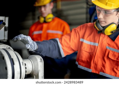 Engineer man checking the status of machine and used wrench to screw some part of equipment at CNC factory. Worker wearing safety glasses and helmet. Maintenance and repairing concept.