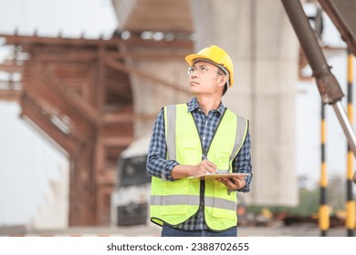 Engineer man with clipboard checklist in construction site, Industrial worker at infrastructure site, Foreman in hardhat in industry containers cargo - Powered by Shutterstock