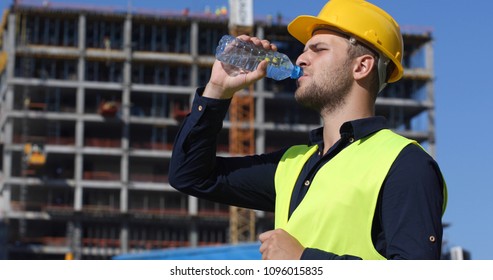 Engineer Man Drink Water in a Hot Summer Day,  Worker Male Have a Break near Under Construction Building