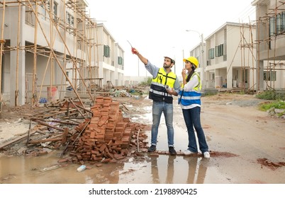 Engineer Man And Female Architect Wear Safety Helmets Discuss Housing Development Project At Construction Site As On Blueprint. Contractor Manager Inspecting House Building Estate Infrastructure