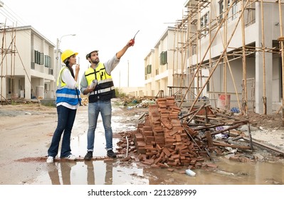 Engineer Man And Female Architect Wear Safety Helmets Discuss Housing Development Project At Construction Site As On Blueprint. Contractor Manager Inspecting House Building Estate Infrastructure