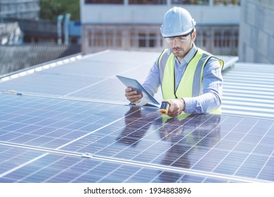 Engineer Man Inspects Construction Of Solar Cell Panel Or Photovoltaic Cell By Electronic Device. Industrial Renewable Energy Of Green Power. Factory Worker Working On Tower Roof.