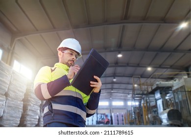 An engineer man making notes on his clipboard in a factory. Concept of Industry - Powered by Shutterstock