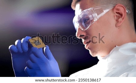 Engineer man in sterile suit is holding Microchip with symbols in modern design factory , futuristic and artificial intelligence concept