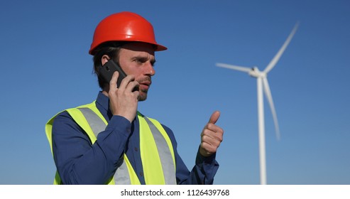 Engineer Man Talking on Mobile Phone with a Partner about Wind Turbines Electricity Production, Green Energy Concept - Powered by Shutterstock