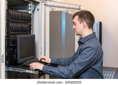 IT engineer with the management console between the server racks in the data center