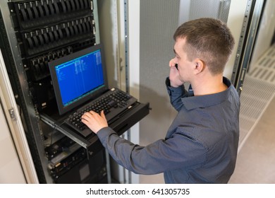 IT engineer with the management console between the server racks in the data center