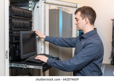 IT engineer with the management console between the server racks in the data center