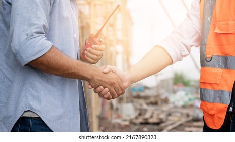 The engineer manager and foreman construction workers shake hands on the construction site