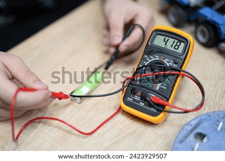 the engineer measures the voltage on the battery with a multimeter