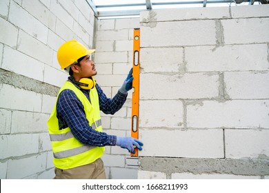 Engineer Measures The Work Out Wall Lightweight Concrete Blocks With A Level At Construction Site.