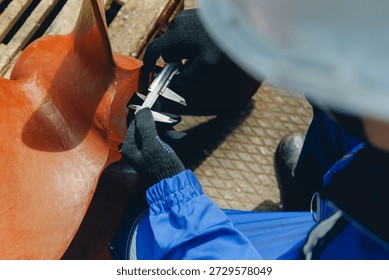 Engineer measuring ship components in industrial shipyard environment.
