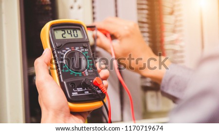 Engineer is measuring voltage or current by voltmeter in control panel