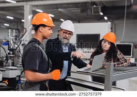 Engineer mentoring apprentice workers in a window factory, discussing production plans and designs on a laptop