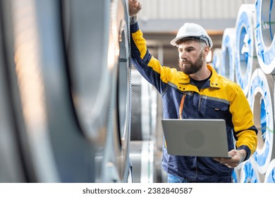 Engineer metal sheet factory worker man inspection on hole rolls of metal carbon steel sheets in factory or warehouse. Metal sheet manufacturing business. - Powered by Shutterstock